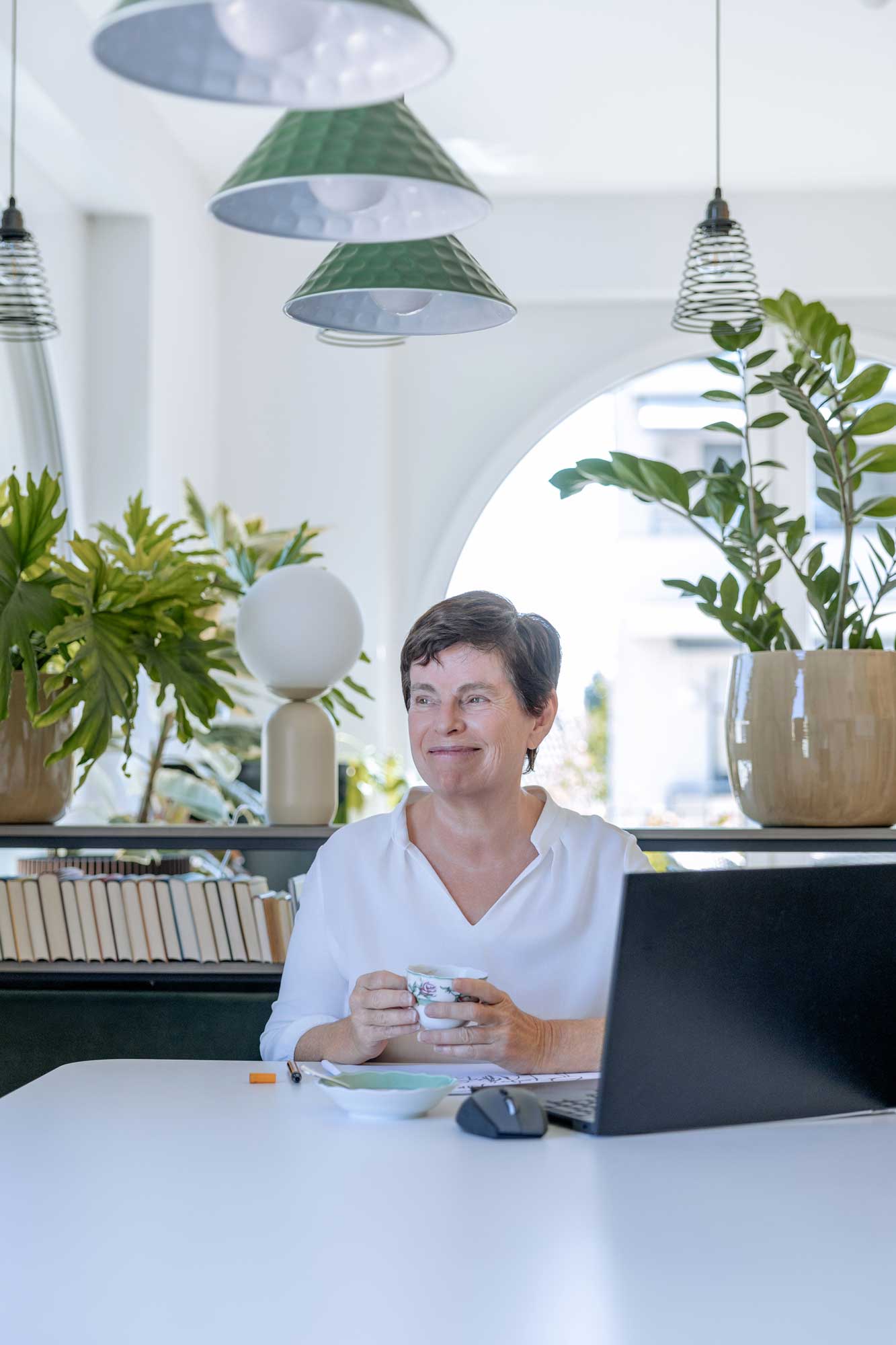 Sabine Peipe am Laptop, im Hintergrund viele Pflanzen